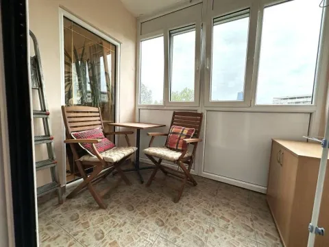 Enclosed balcony with a wooden table, chairs, and tiled flooring. - image 11