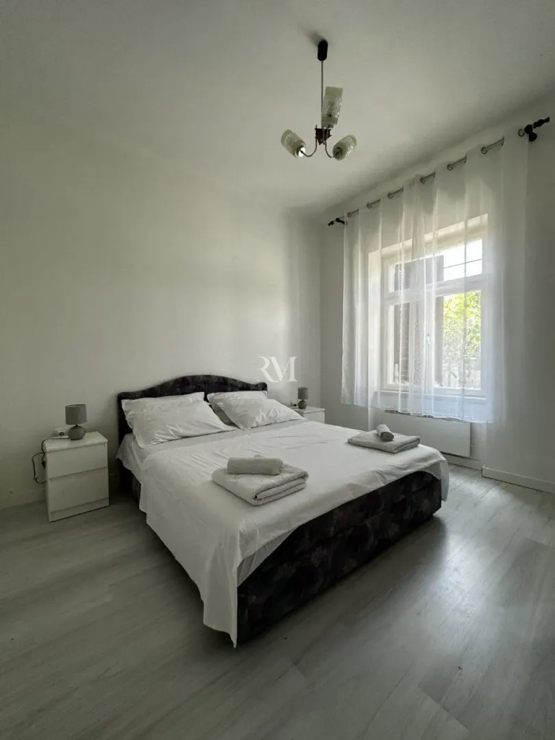 Bright bedroom with a double bed, white linens, and a window.
