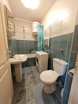 Small bathroom with a bathtub, washbasin, washing machine, and toilet. - image 10