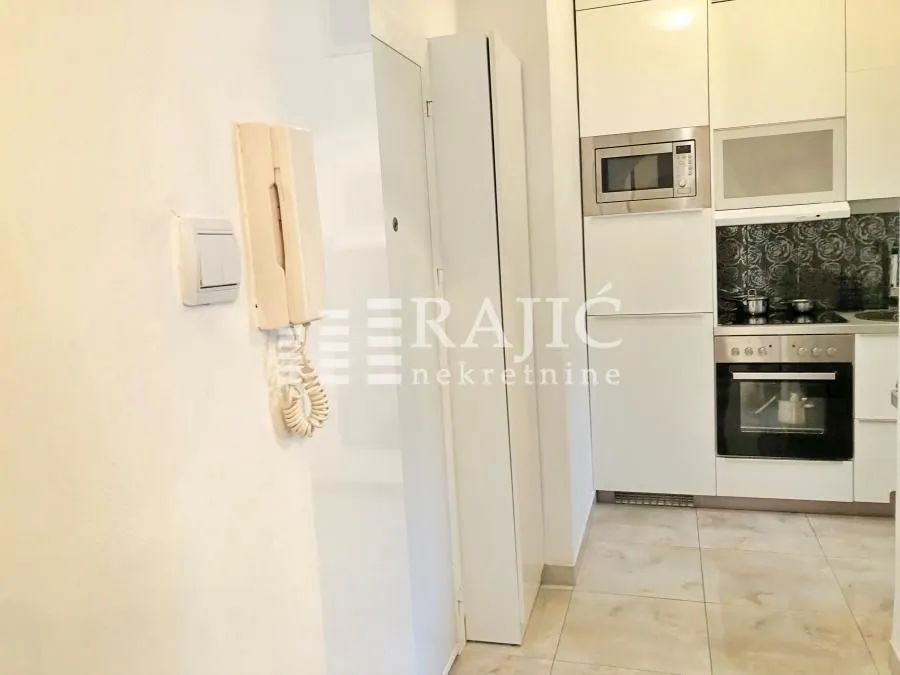 View of the kitchen with white cabinetry and built-in oven.