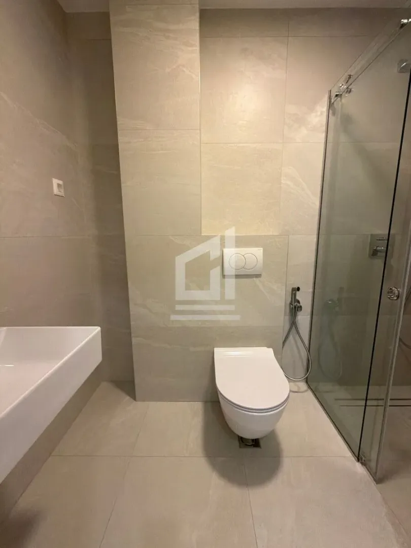 Savremeno opremljeno kupatilo sa tuš kabinom i sanitarijama u bež tonovima.