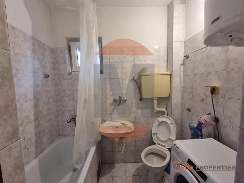Manje kupatilo sa kadom, umivaonikom, WC šoljom i veš mašinom.