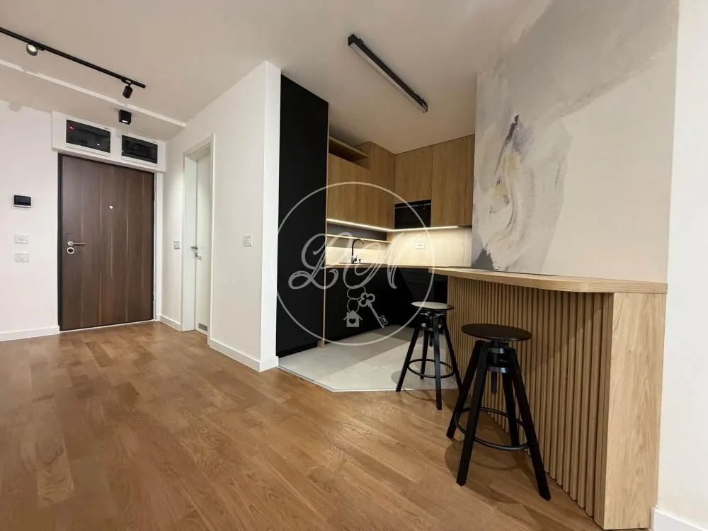 Small kitchen with a bar counter and wooden flooring in the hallway.
