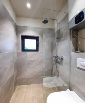 Savremeno opremljeno kupatilo sa tuš kabinom i pločicama u neutralnim tonovima. - image 13