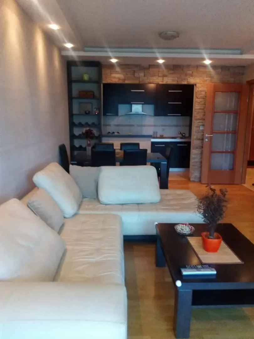 Bright living room featuring a spacious corner sofa and a kitchen in the background.