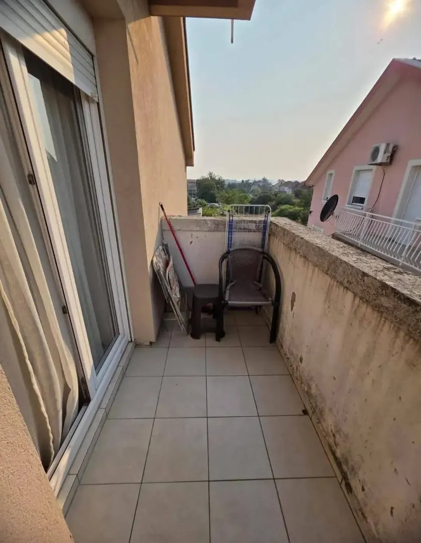 Manji popločani balkon sa stolicama i sušačem za veš.