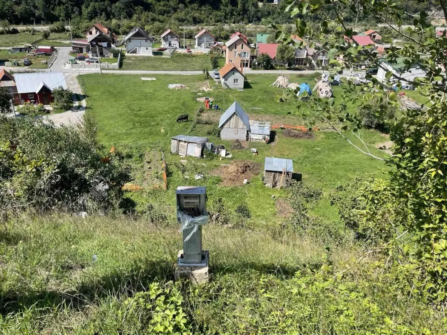 Pogled na zeleni plac i okolne kuće u seoskom području.