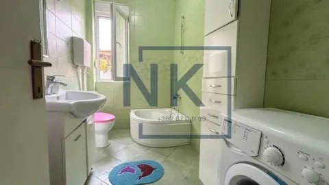 Small bathroom with a bathtub, sink, toilet, and washing machine. - image 3