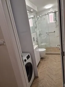 Pogled iz hodnika na moderno uređeno kupatilo sa tuš kabinom i mašinom za pranje veša. - image 14