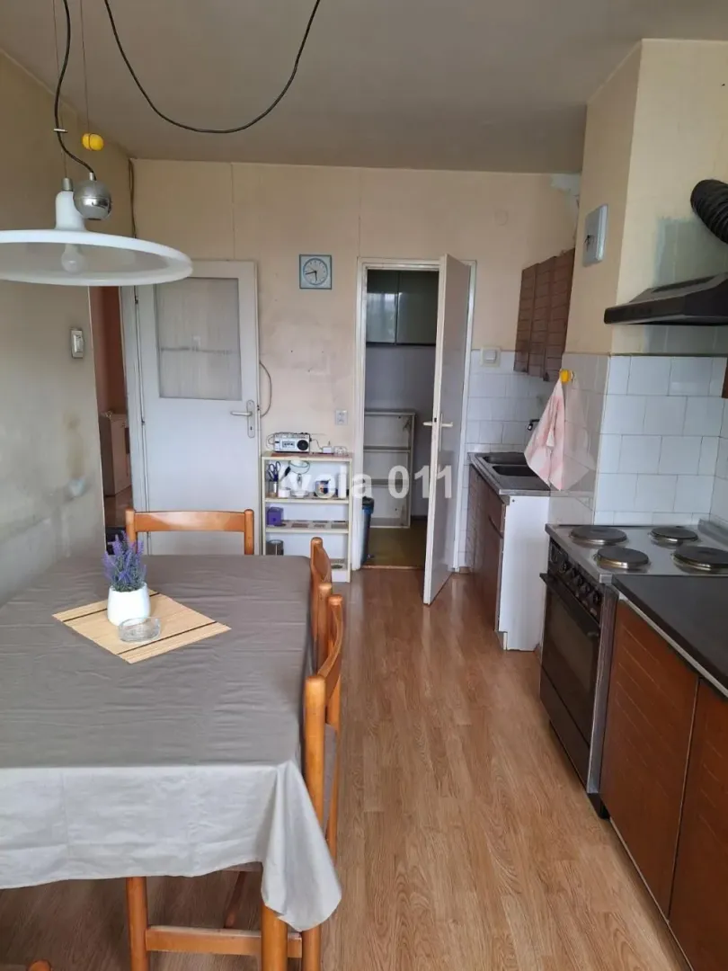 Starija kuhinja sa trpezarijskim stolom i drvenim elementima.