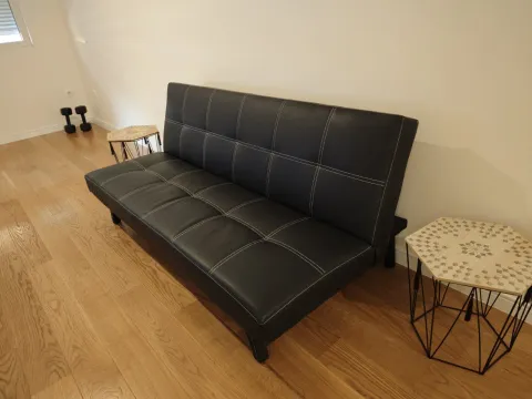Crna kožna sofa sa malim pomoćnim stolovima na drvenom podu. - image 12