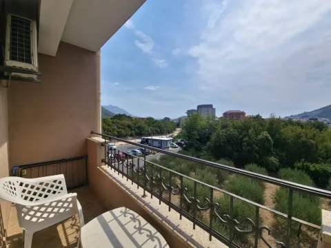 Small furnished balcony with a view of greenery and surrounding buildings. - image 11
