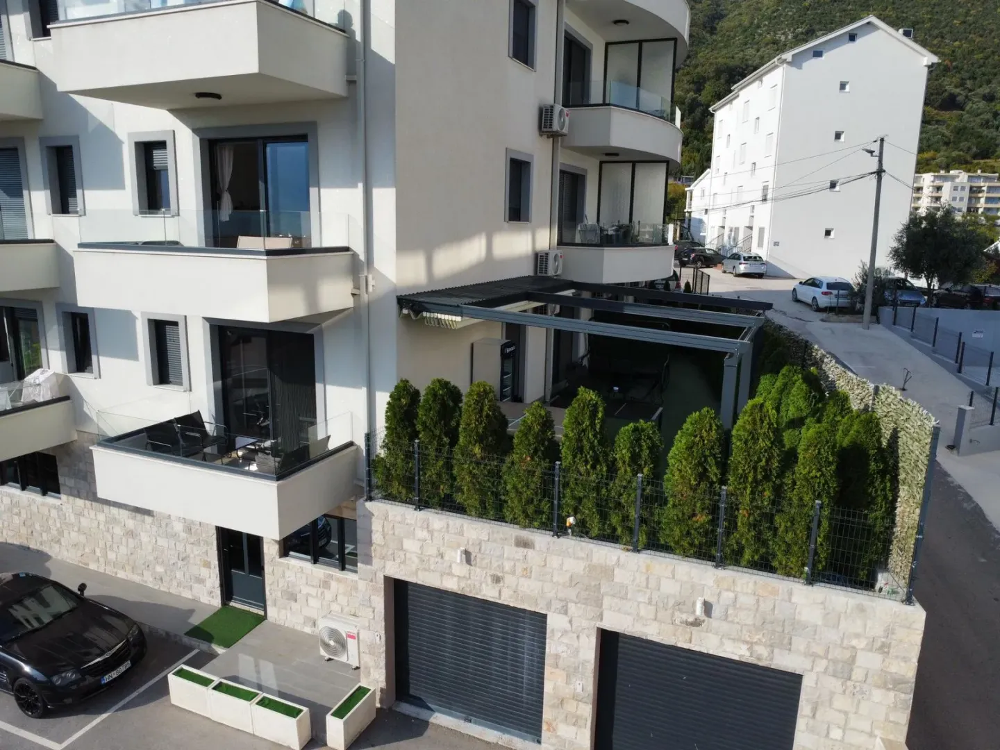 Pogled iz vazduha na spoljašnjost stambene zgrade sa terasama i garažama.