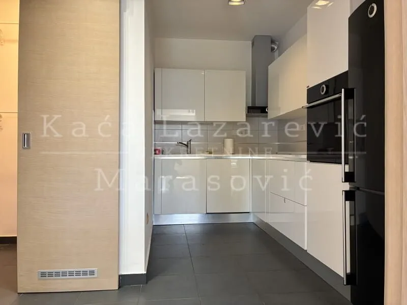 Modern white kitchen with built-in appliances and dark floor tiles.