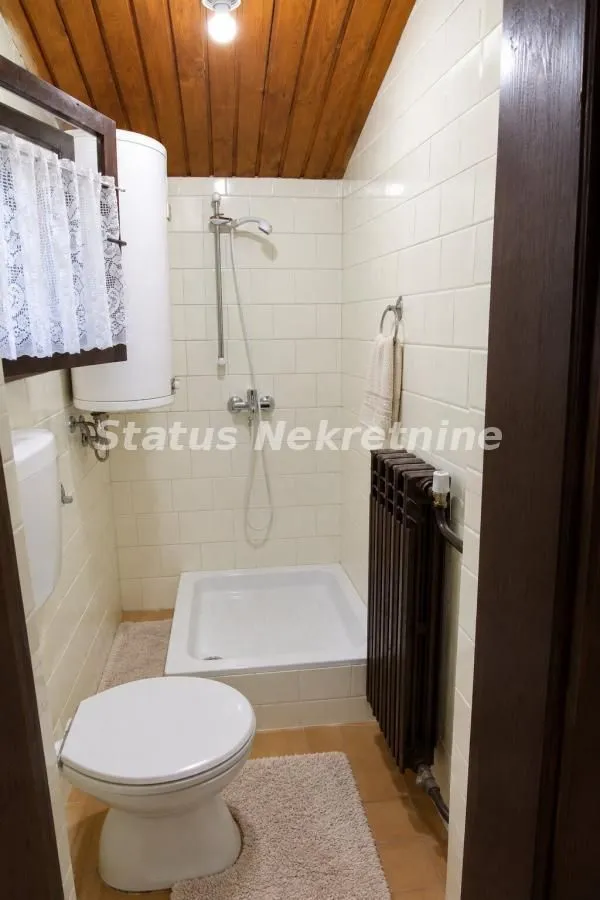 Manje kupatilo sa tuš kabinom, WC šoljom i bojlerom.