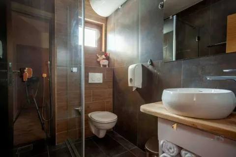 Savremeno opremljeno kupatilo sa tuš kabinom, konzolnom šoljom i umivaonikom na drvenoj pločici. - image 5