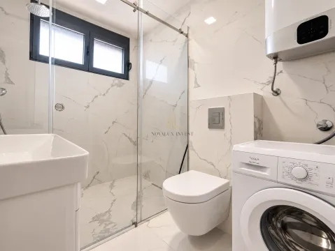 Modern bathroom with a walk-in shower, toilet, washbasin, and washing machine. - image 9