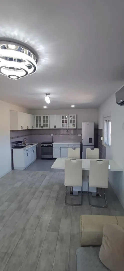Modern kitchen with white cabinetry and a dining table.