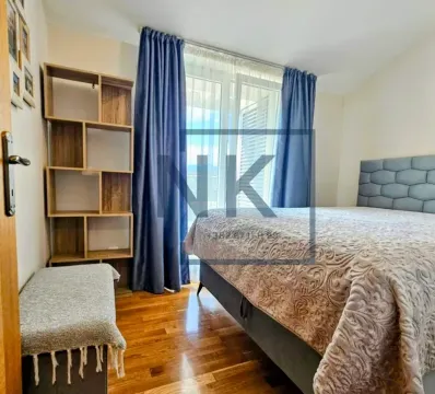 Bedroom with a double bed, wooden shelving unit, and balcony doors with blue curtains. - image 5