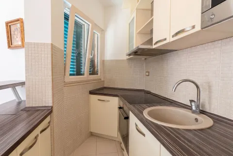 Compact bright kitchen with built-in cabinetry and a sink by the window. - image 13