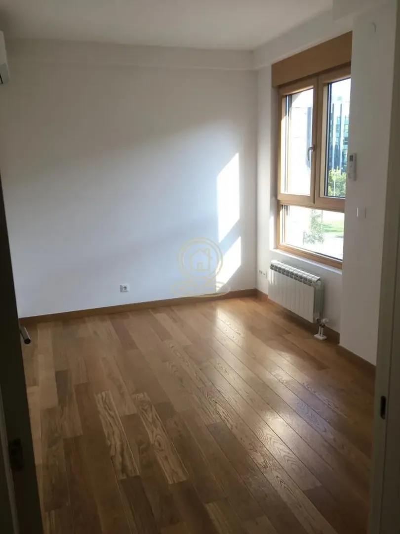 Empty room with wooden flooring and a window.