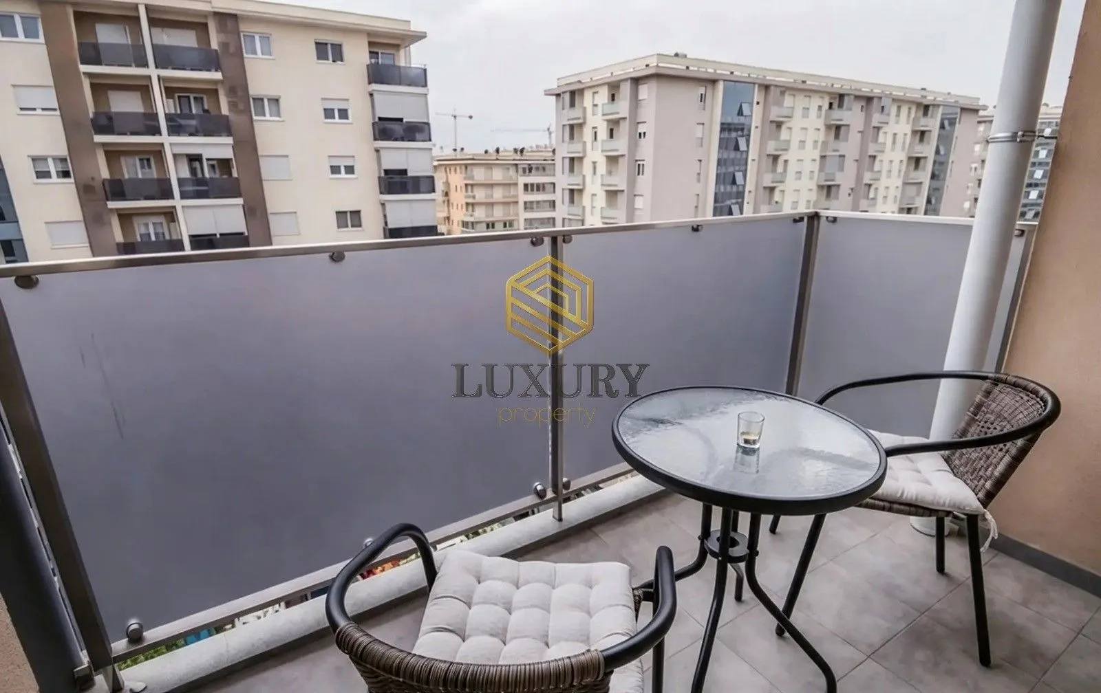 Furnished terrace with a small table and chairs overlooking buildings.