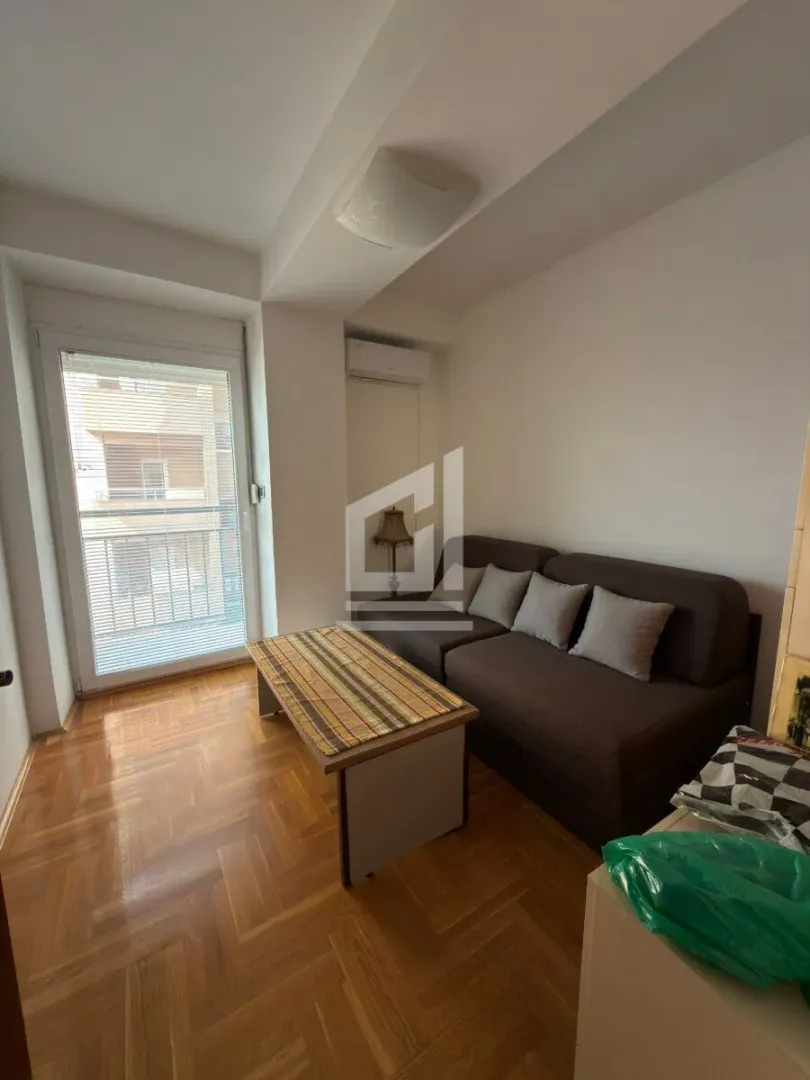 Dnevna soba sa braon trosjedom, stočićem i izlazom na balkon.
