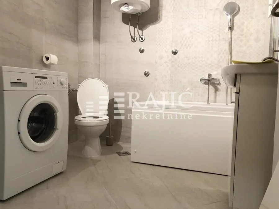 Modernly equipped bathroom with a bathtub and a washing machine.