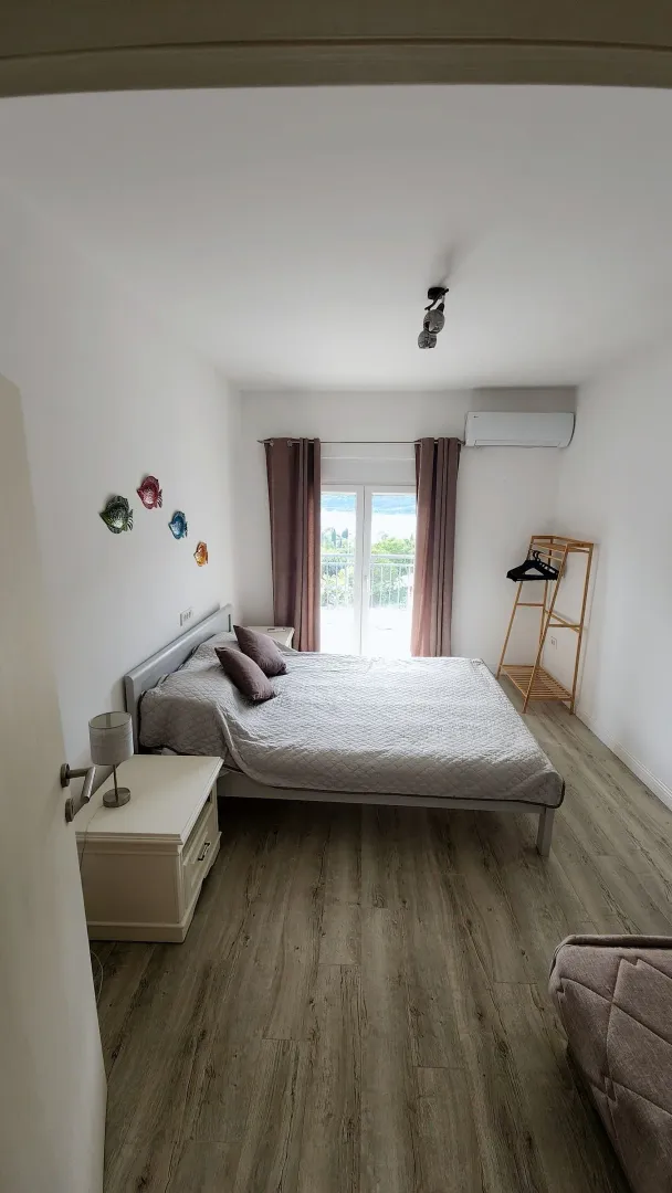 Spavaća soba sa bračnim krevetom, noćnim stočićem i izlazom na terasu.