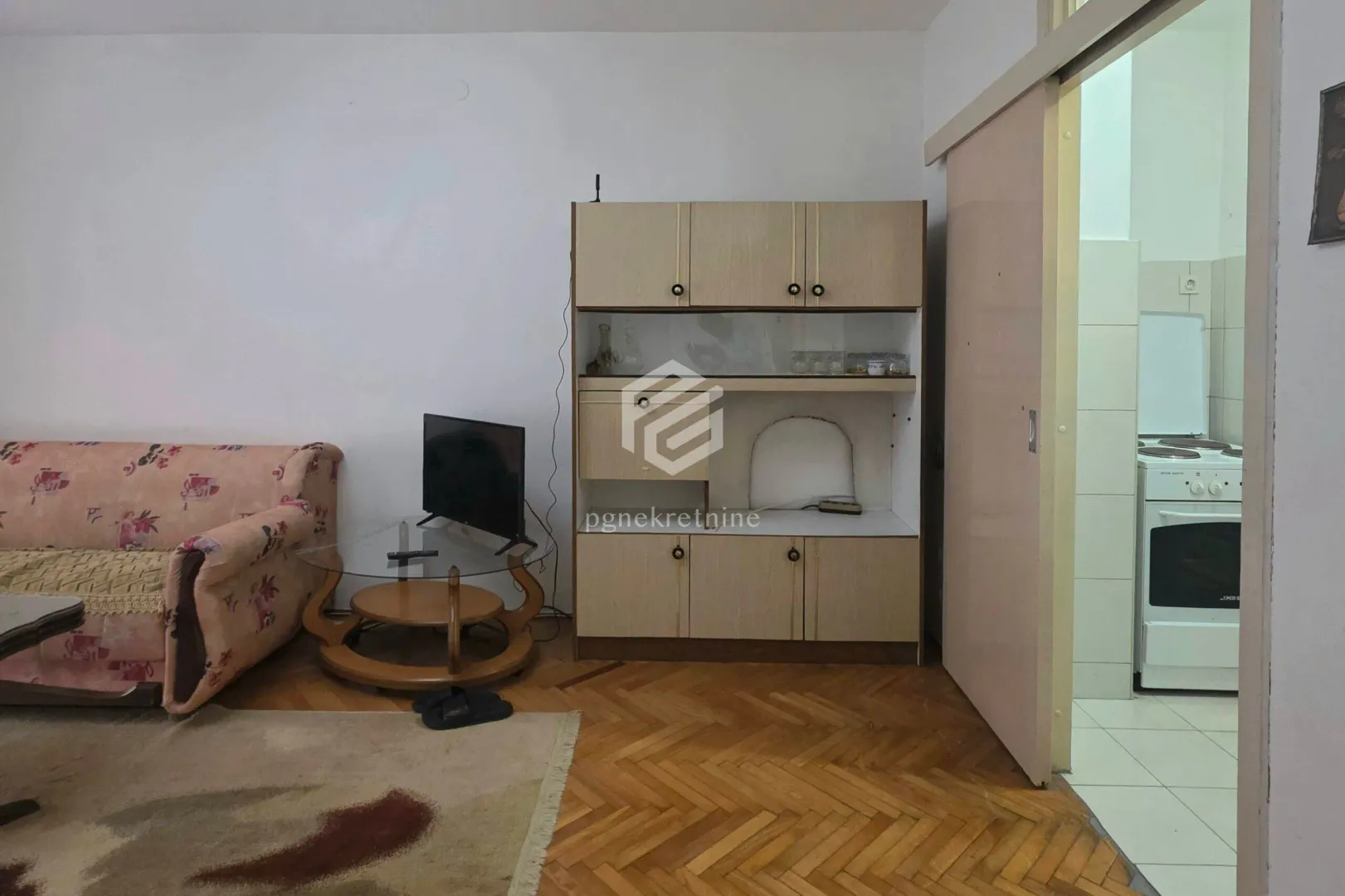 Living room with a sofa, TV, and a view of the kitchen.