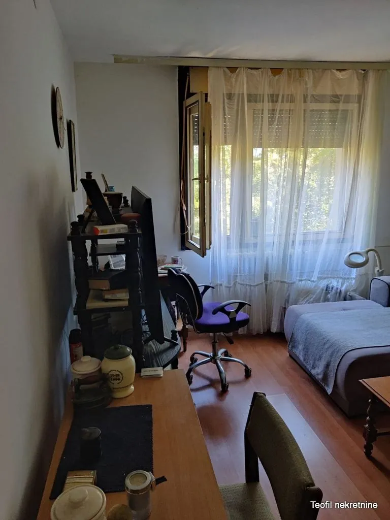Manja soba sa radnim stolom i kaučem pored prozora.