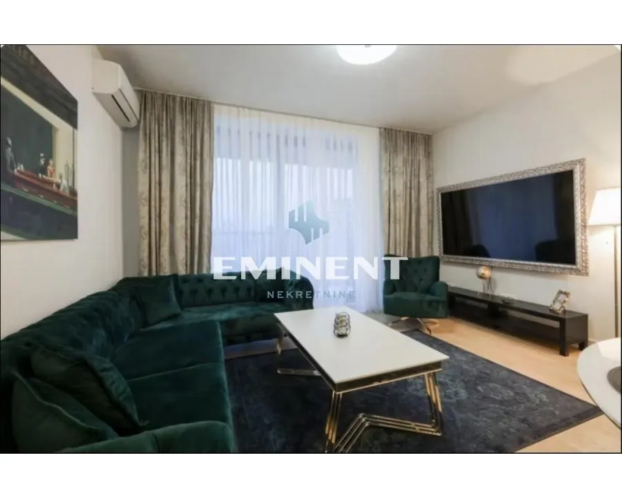 Living room with a green sectional sofa, coffee table, and wall-mounted TV.