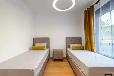 Spavaća soba sa dva singl kreveta, noćnim stočićem i žutim zavesama. - image 3