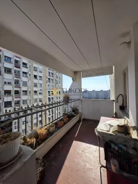 Natkriveni balkon sa metalnom ogradom i pogledom na okolne zgrade. - image 18