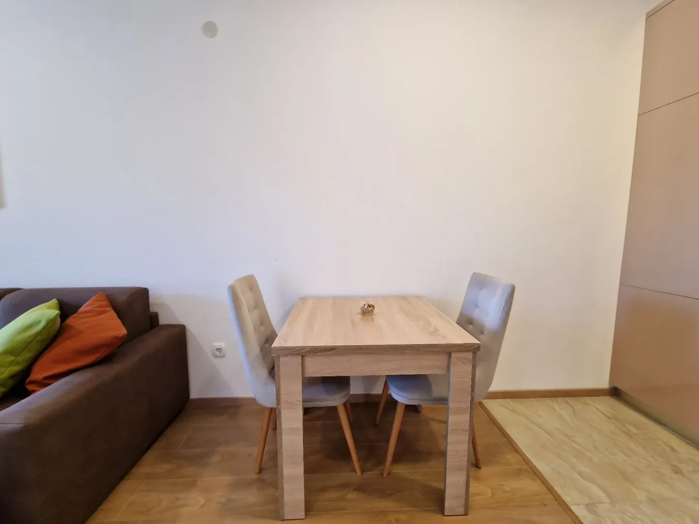 Trpezarijski sto sa dvije stolice pored kauča.