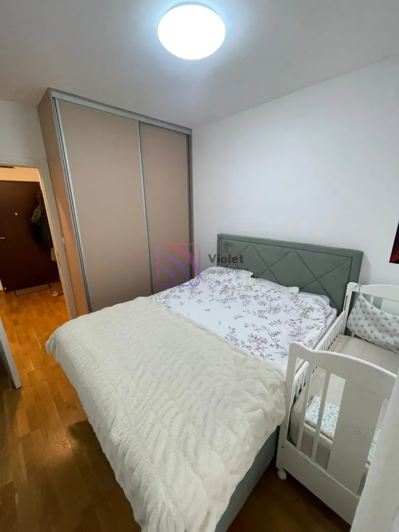 Spavaća soba sa bračnim krevetom, krevetcem za bebe i ugradnim plakarom.