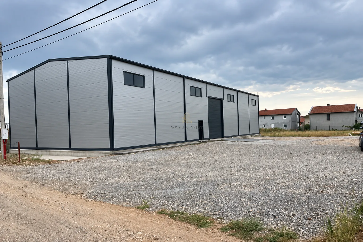 View of the exterior of a modern prefabricated building with warehouse space and a gravel yard.