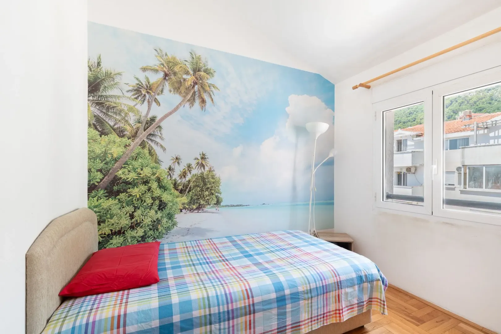Bedroom with a bed and a beach-themed accent wall.