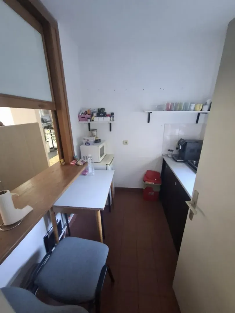 Manja kuhinja sa radnim elementima, stolom i šankom.