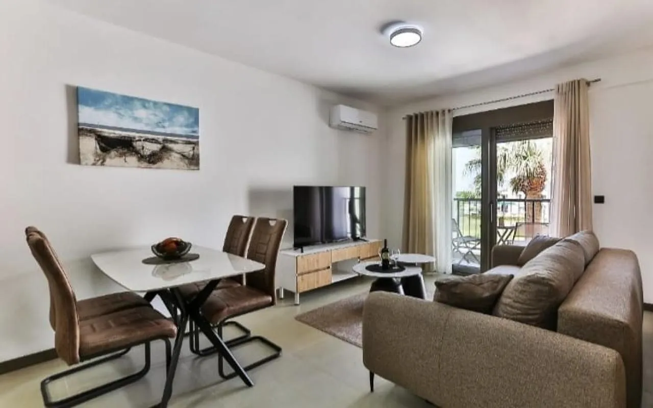 Living room with a sofa set, television, and dining table.