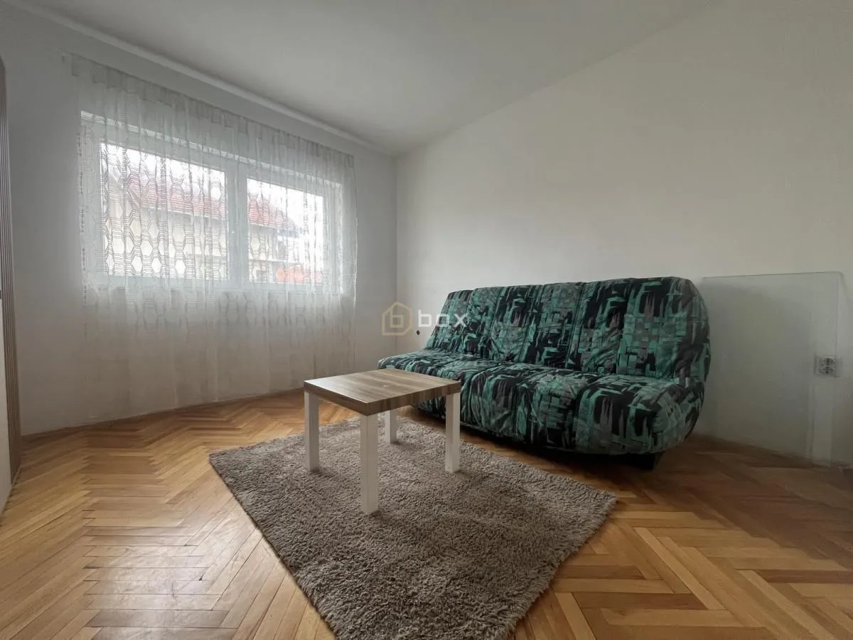 Living room with a sofa, coffee table, and parquet flooring.