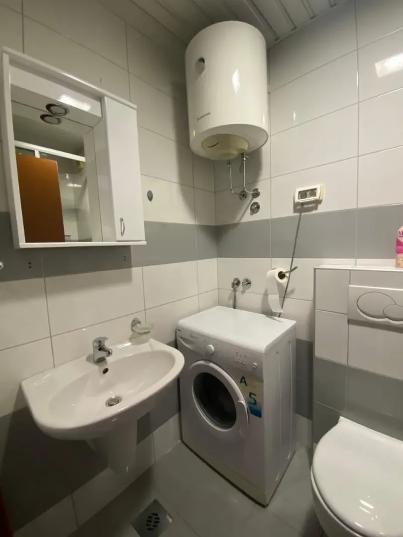 Kupatilo sa lavaboom, veš mašinom, bojlerom i toaletom.
