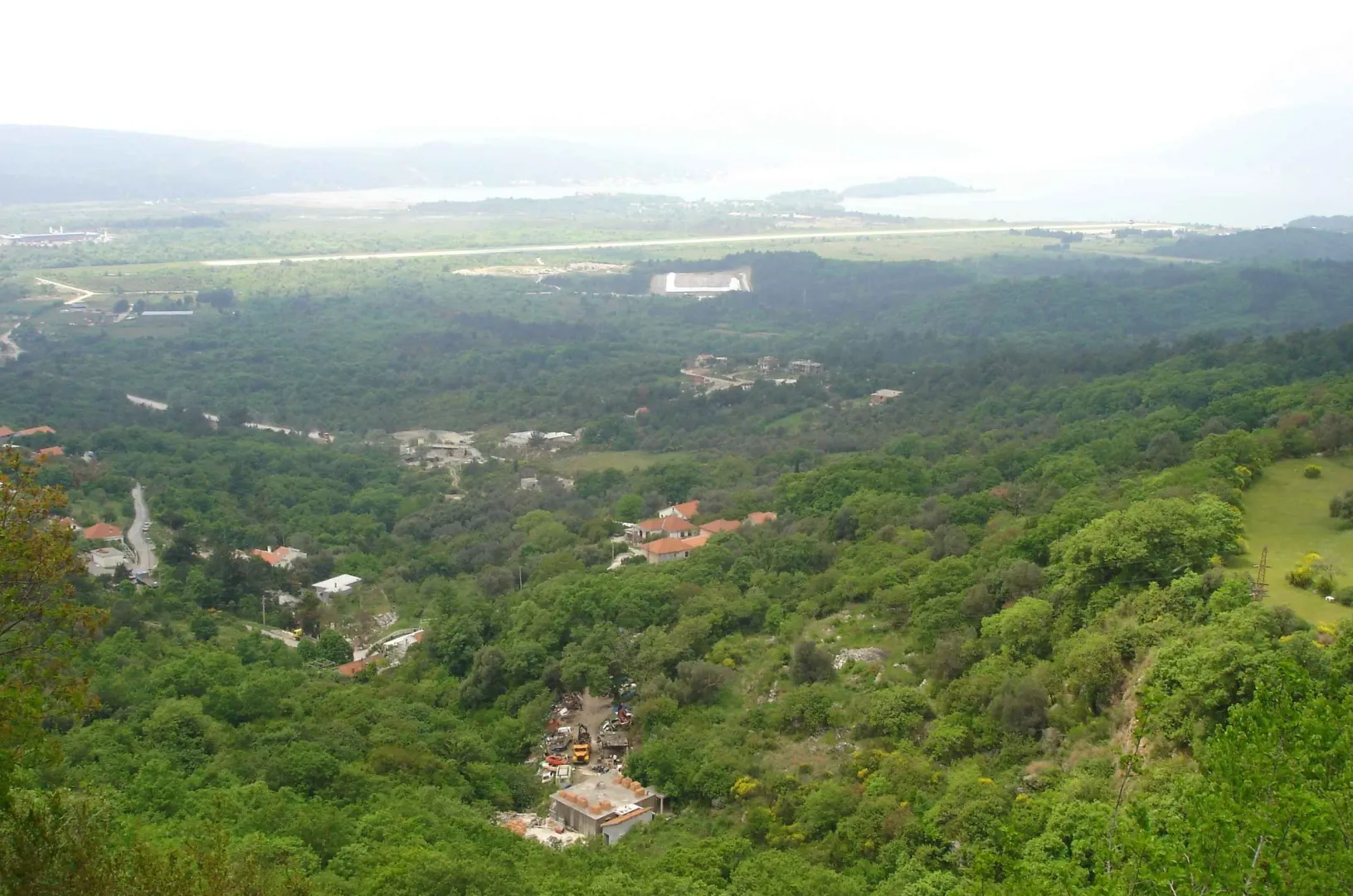 Panoramski pogled na zelena brda i more u daljini.