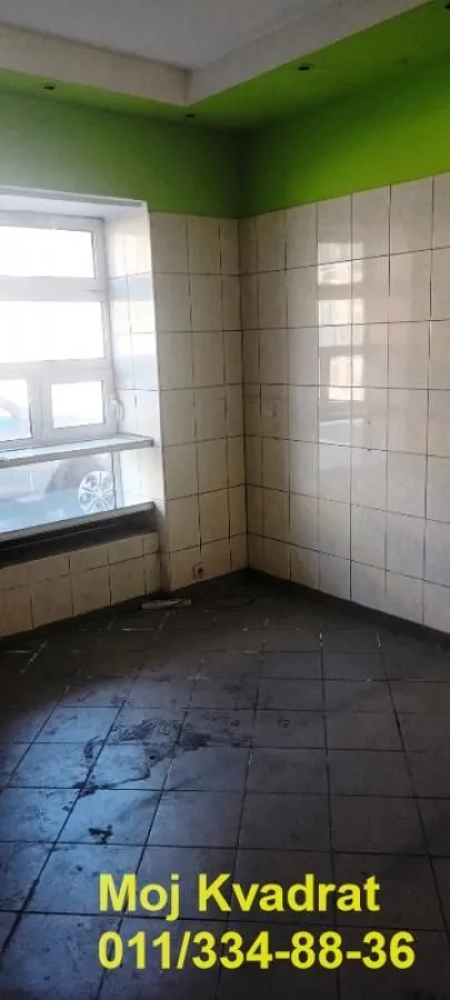 Prazna kuhinja sa pločicama na zidovima i podu i prozorom.