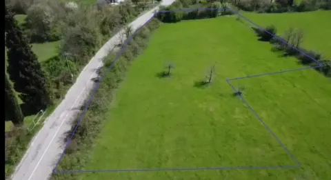 Pogled iz vazduha na zemljište sa ucrtanim granicama parcele pored puta. - image 2