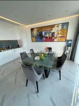 Dining area with a glass table and modern grey chairs next to the kitchen. - image 10