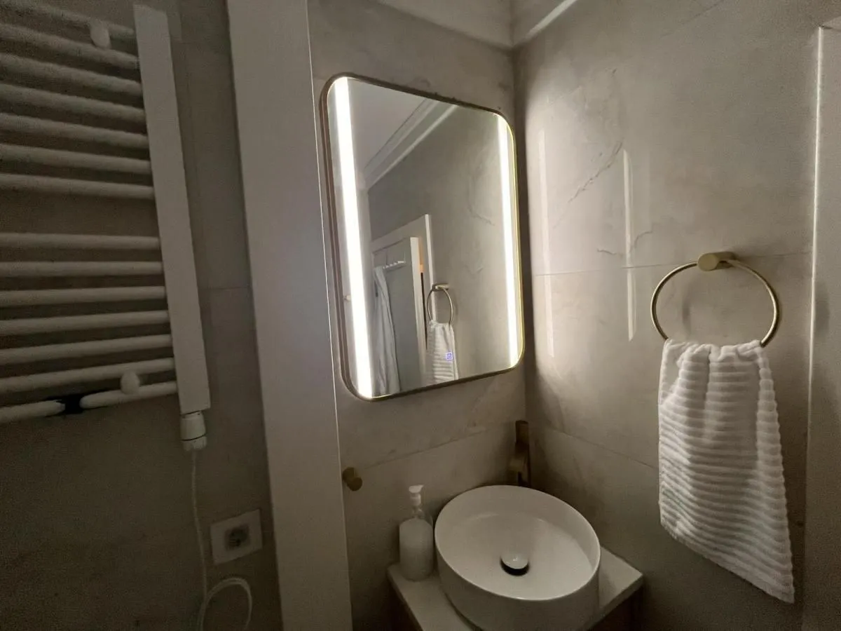 Detalj kupatila sa umivaonikom, ogledalom sa osvetljenjem i radijatorom.