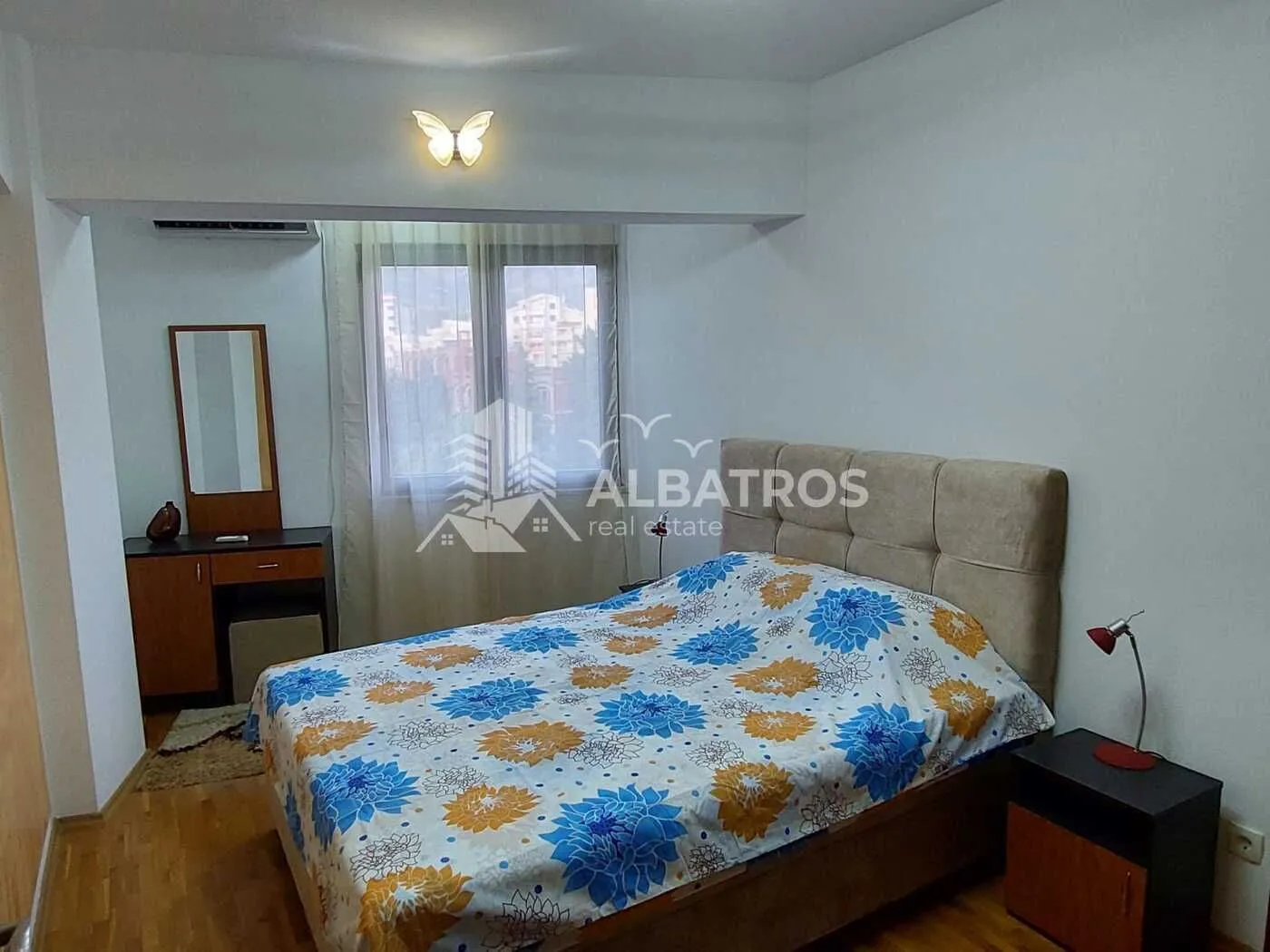 Furnished bedroom with a double bed, nightstand, and vanity table.