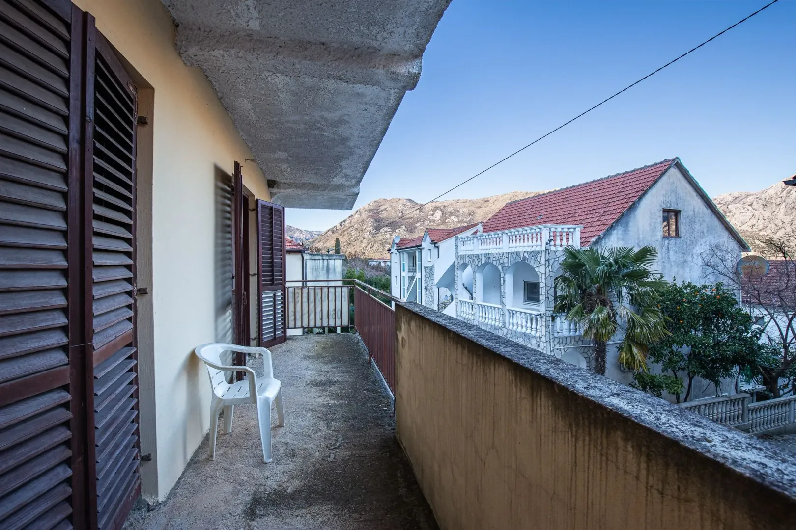 Natkriveni balkon sa pogledom na okolne zgrade i planine.