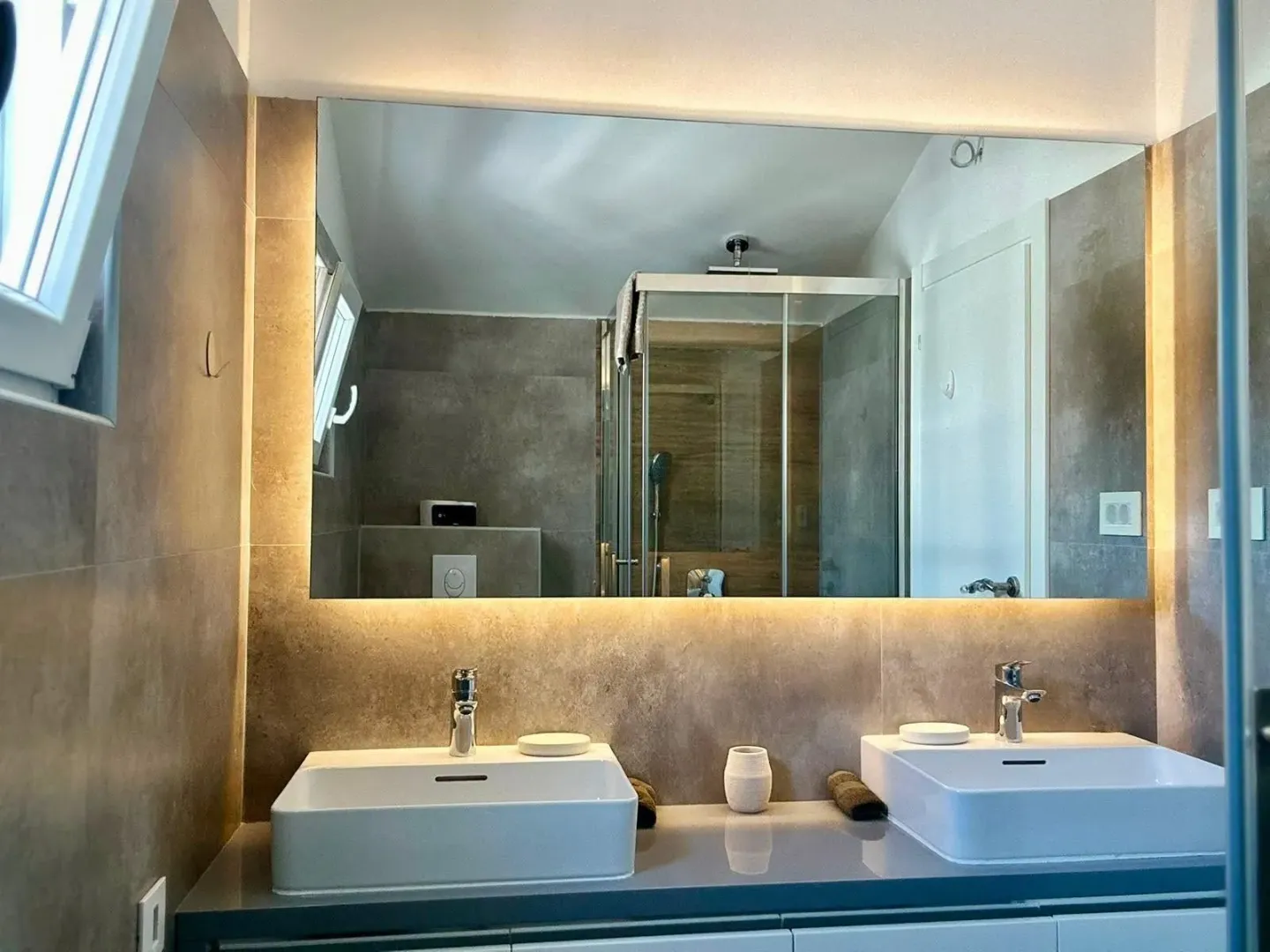 Modern bathroom with double sinks and a large backlit mirror.